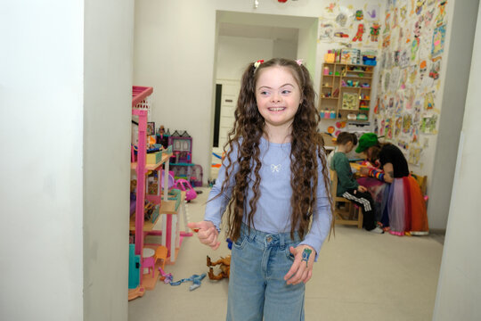 Happy girl with down syndrome smiling in playroom, commercial diversity concept