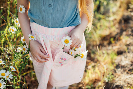 Young Girl Putting Daisies in Skirt Pocket