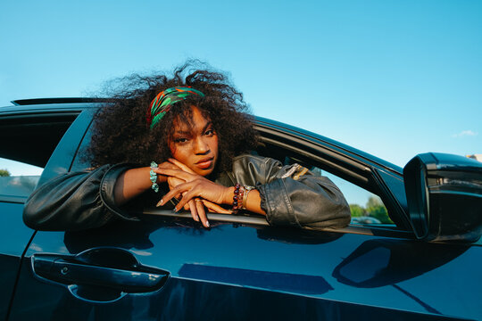 woman with natural curly hair leaning out of a modern car window