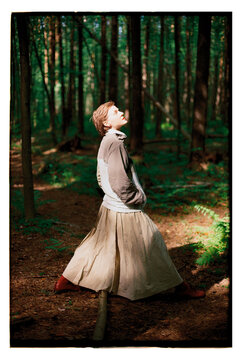 Girl standing in a forest with sunlight filtering through trees