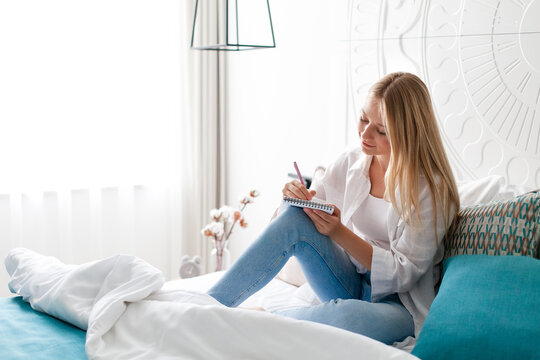 Young woman relaxing in bed. Girl drawing, writing in journal. Art therapy, self-care, female wellness and cozy home. Mindful morning routine, slow living, analog lifestyle