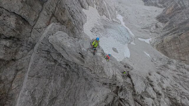 Two hikers descending an iron ladder near Bocca degli Armi on Via Ferrata Bocchette Centrali
