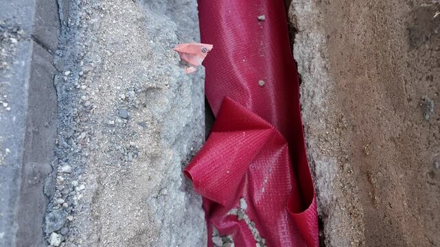 Construction trench with red protective conduit and paving stones