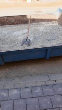 Construction site skip filled with gravel and shovels ready for work