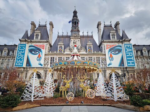 Paris, France - December 10, 2025: A festive winter scene of Hotel de Ville, Paris City Hall with a colorful carousel on the square and Christmas trees decorated with lights