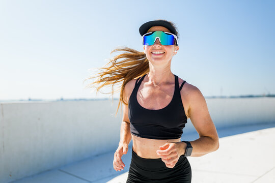 Bright sunshine inspires a joyful run along the urban landscape with a spirited woman embracing fitness and freedom