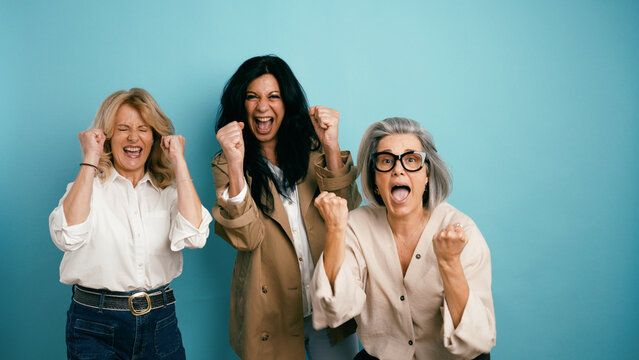Three diverse women expressing joy and empowerment, cheering loudly with clenched fists, celebrating victory or a goal achieved