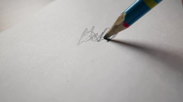 A sharp pencil writes the cursive word you on a sheet of textured white paper. The close-up detail highlights the gray graphite lead trail and the blue wooden body of the pencil