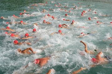 Group of swimmers in red caps competing in open water sea swimming competition background © Ekaterina