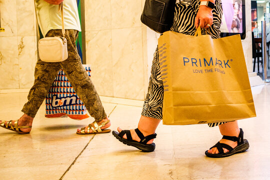 Waist Down View Of Two Women Walking Together Side by Side Holding B&M and Primark Shopping Bags