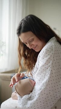 Tender moment of a mother breastfeeding her newborn child, holding the infant close while sitting at home, showcasing the intimate connection and nurturing aspect of parenthood