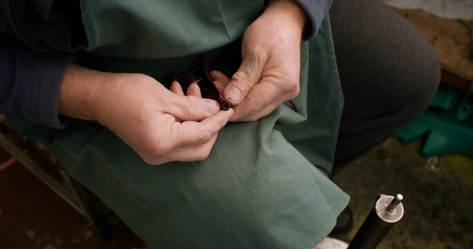 Tailor working. Craft tool. Unrecognizable professional expert man hands with heel leather for footwear manufacturing in workshop.