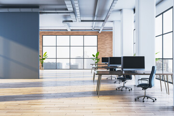 Obraz premium Bright open plan coworking office interior with wooden floor, computer monitors on shared desks, blue wall and panoramic city view windows. 3D Rendering