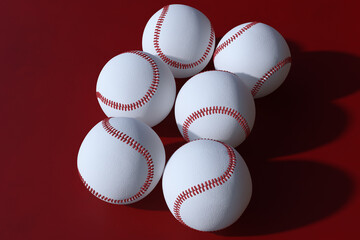Obraz premium Group of six white baseballs with classic red stitching arranged on dark red background, showing team sport equipment and championship game theme. 3D Rendering