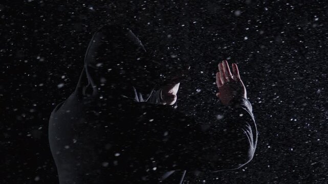 Faceless man hides in hoodie. Faceless figure stands against snow. Dark faceless concept shows identity. Snowy faceless scene feels creepy.