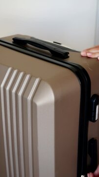 Close-up of woman unzipping hard shell Travel suitcase before packing.