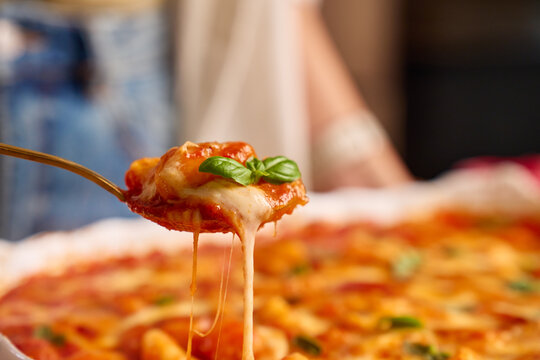Gnocchi with tomato sauce and melted cheese lifted on serving spoon with basil garnish