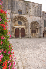 Fototapeta premium Romanesque church facade in Avallon with vibrant geraniums