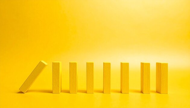Yellow domino blocks falling in sequence symbolizing cause and effect motion