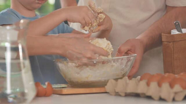 Family shaping and cutting dough on a floury worktop at the kitchen worktop