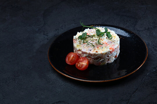 Traditional Olivier salad on dark background. New Year's appetizer. Copy space