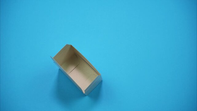 A top-view of die-cut cardboard blank transforming into a fully assembled packaging box. The paperboard template fold step by step along the crease lines. Stop-motion animation