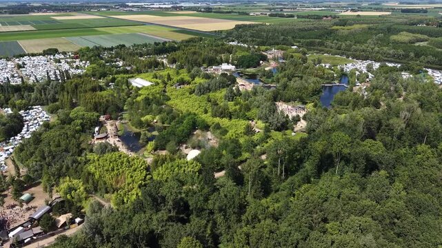 Aerial drone video panning right to left over the Wildeburg music festival in the Netherlands. Distant shot shows the outdoor event surrounded by green nature with no recognizable faces.