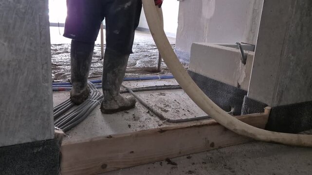 Slow motion video of construction team pouring lightweight polystyrene concrete and checking floor level thickness in a new build house.