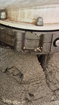 Vertical 9:16 macro shot showing the structure of lightweight polystyrene concrete pouring into a mixer trough.