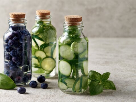 Fresh fruit and vegetable infused water in glass bottles on countertop