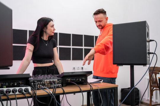 Music lesson with two DJs discussing sound mixing approaches at studio console. DJs, music lesson, studio, discussion, mixing