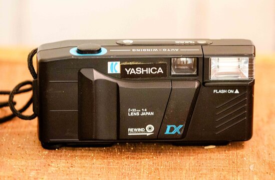 Brazil, December 26, 2016: close-up of a vintage DX Yashica point-and-shoot 35mm film camera with built-in flash, auto-winding feature, and 33mm lens, resting on a wooden surface,
