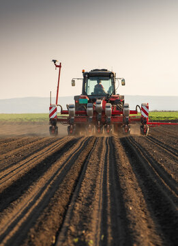 Seeder attached to tractor planting crops on freshly tilled soil