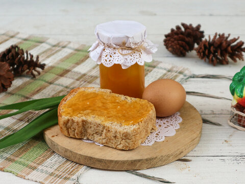 A bottle of rich, sweet kaya, also known as srikaya jam, paired with a slice of toast. Crafted from eggs, sugar, coconut milk, and the essence of pandan leaves.
