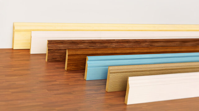 Baseboards with various profiles standing on hardwood surface. 3D illustration