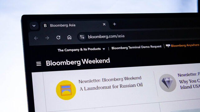 Close-up of computer screen displaying news. Person browsing Bloomberg Weekend online. Reading financial news on laptop.