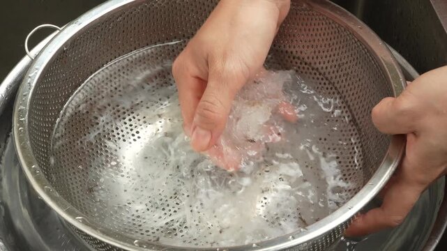 Displaying clean and translucent edible swiftlet bird nest strands on a hand over a colander.