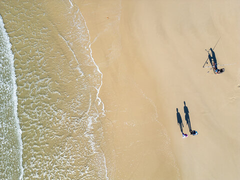 Top-Down Drone View of a Couple, a Fisherman and a Bicycle on the Beach