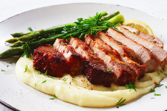 Sliced pork chop, with mashed potatoes and asparagus, on a white plate, homemade, no people,