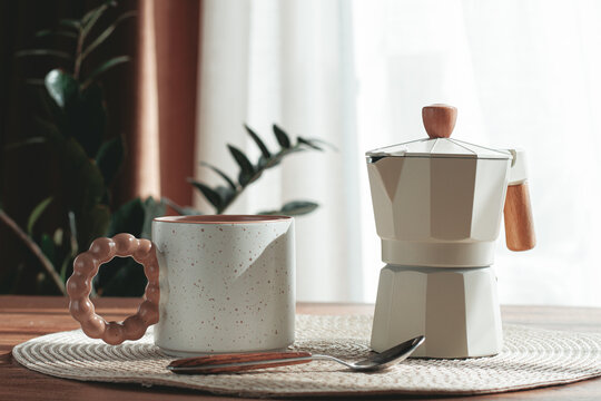 Making morning coffee, geyser coffee maker and mug, on a wooden table, natural light, no people,