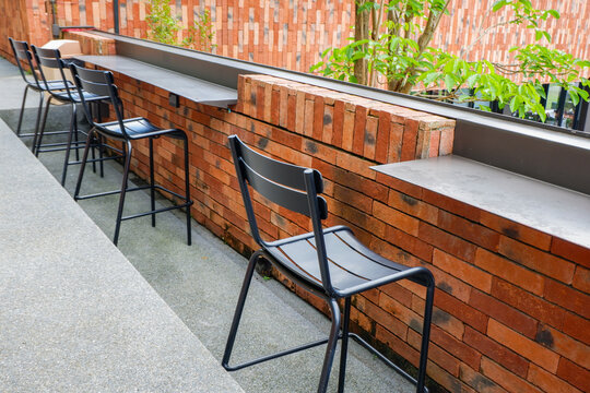 Wooden table and chair set in garden on a sunny day,outdoor seating for restaurant or cafe,Neat paved patio with sitting area and small garden in forest.