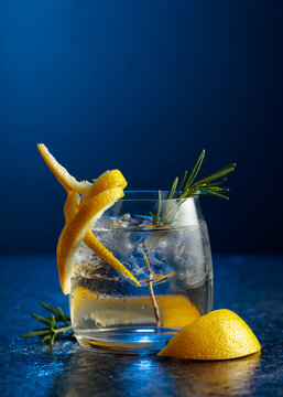 Gin and tonick cocktail in a fogged up glass on a dark blue background.
