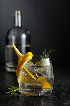 Gin and tonick cocktail in a fogged up glass on a black table.