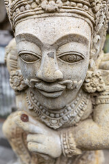 Obraz premium Closeup of face of stone carved statue of a god on wall of Hindu temple in Bali