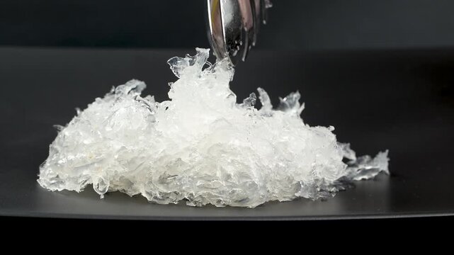 Macro of beautiful clean and translucent processed edible bird nest strands on a black plate.