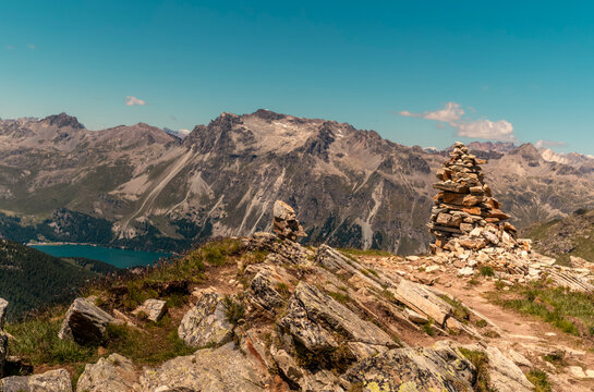 Alpine Hiking Trail with Cairns and Snowcapped Peaks in Engadin Valley Switzerland