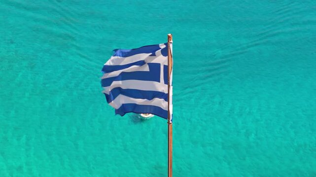Aerial drone view of a small boat flying the Greek flag across the crystal-clear turquoise sea off Gramvousa island, Gramvousa, Greece