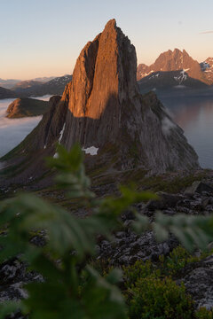 Segla peak illuminated by golden hour sun over misty sea