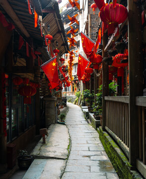 Winding Chinese alleyway with hanging red lanterns and flags