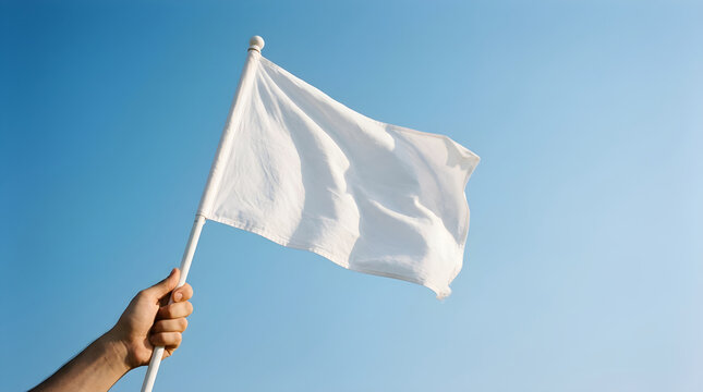 A hand holding a white flag against a clear blue sky. Symbolizing peace, surrender, or a truce in a corporate or political negotiation context.